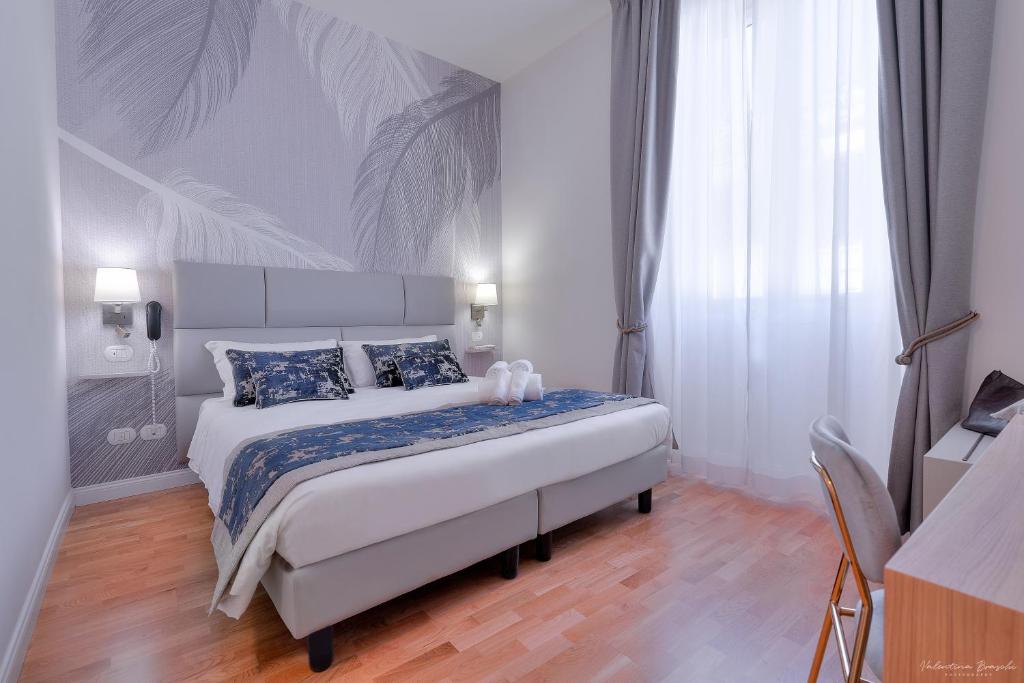 a bedroom with a large white bed with blue pillows at Hotel Cosmos in Florence