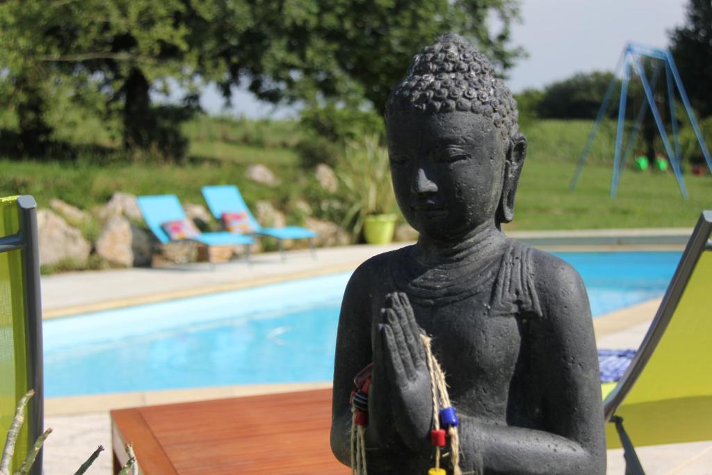 eine Statue vor einem Pool in der Unterkunft Au Petit Bernerot - Les gîtes de l'Arbre Voyageur in Eauze