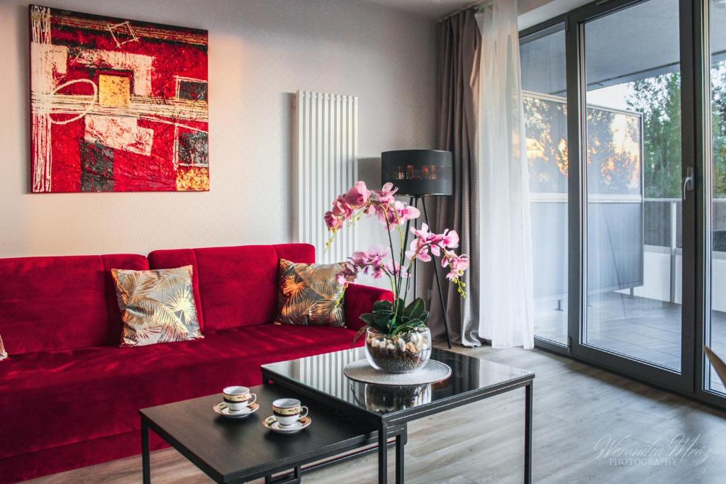 uma sala de estar com um sofá vermelho e uma mesa em D Apartments Centrum Jurowiecka III em Bialystok