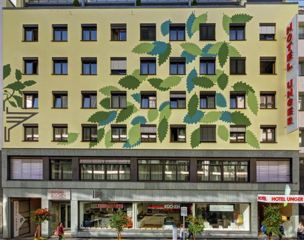 un grand bâtiment jaune avec un arbre sur lui dans l'établissement Hotel Unger, à Stuttgart