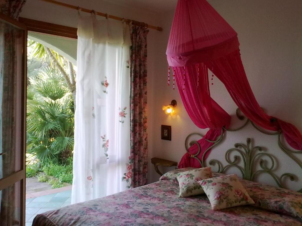 Schlafzimmer mit einem Bett mit rosa Vorhängen und einem Fenster in der Unterkunft Villa Perla in Capoliveri