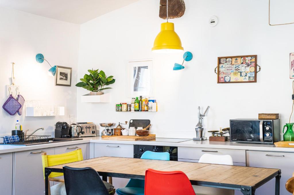a kitchen with a wooden table and colorful chairs at Lumineux Aix Plein Centre avec Parking privé Gratuit in Aix-en-Provence