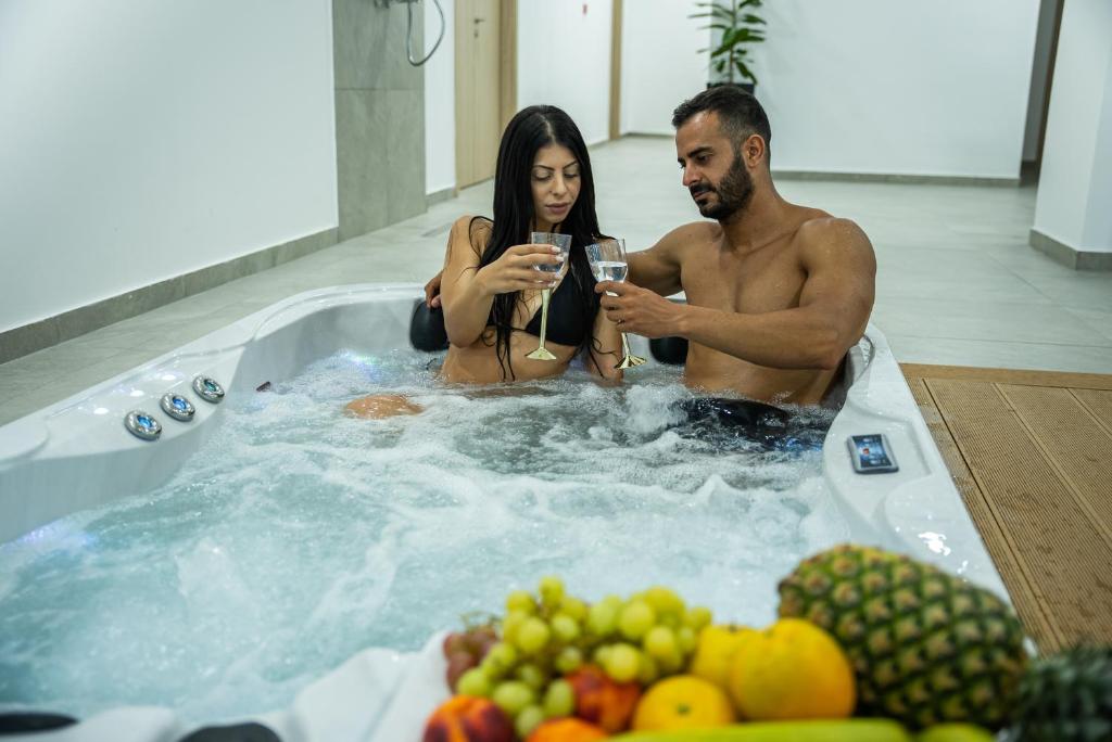 Ein Mann und eine Frau in einer Whirlpool-Badewanne mit Obst in der Unterkunft Caramela Luxury Apts in Ayia Napa