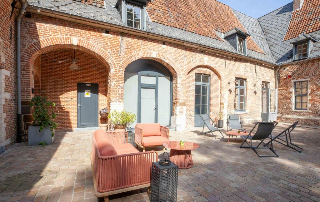 a patio with chairs and tables and a brick building at Hotel The Lodge Heverlee in Leuven