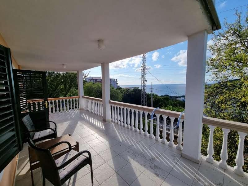 a porch with two chairs and a view of the ocean at Дом для семейного отдыха в Утехе, Черногория in Utjeha