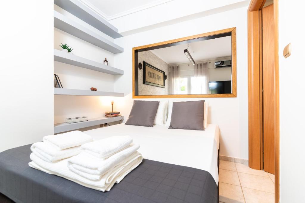 Schlafzimmer mit einem Bett mit weißer Bettwäsche und einem Spiegel in der Unterkunft F & B Collection - Apartment for 4 in Thessaloniki