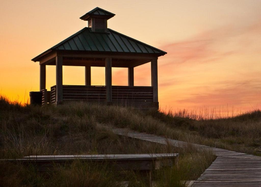 a gazebo on a hill with a sunset in the background at Shutters on the Banks in Kill Devil Hills