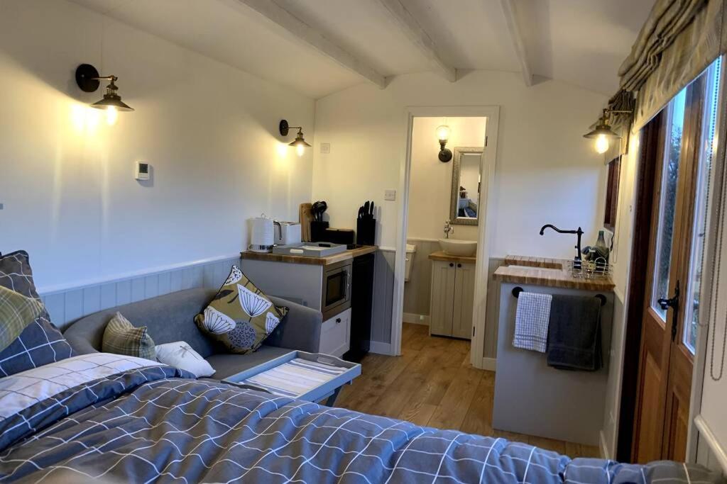 een slaapkamer met een bed en een badkamer met een wastafel bij Idyllic Shepherds Hut, Bylaugh, in private wildflower meadow in Swanton Morley