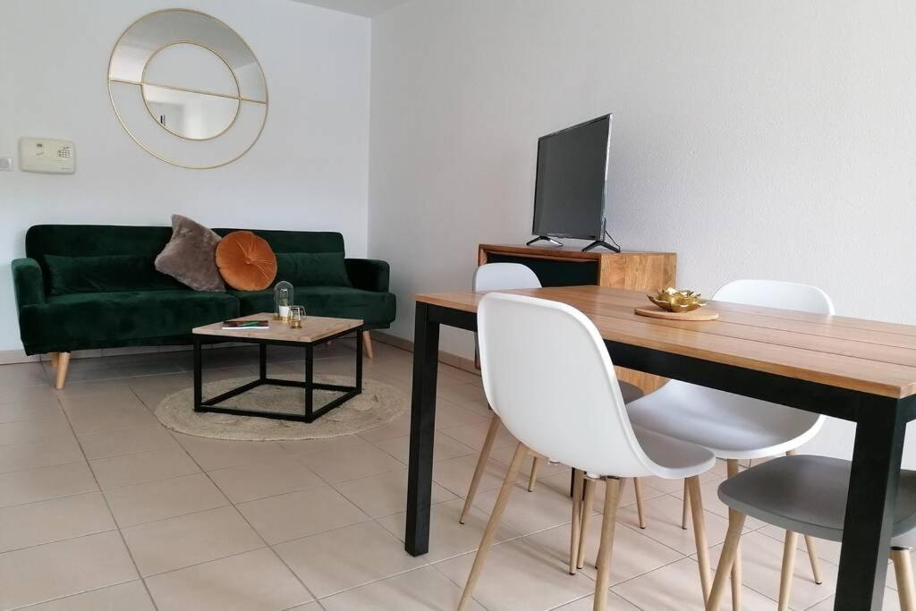 ein Wohnzimmer mit einem Tisch und einem grünen Sofa in der Unterkunft T2 entier - Hyper centre - Cosy home in Grenade-sur-Garonne
