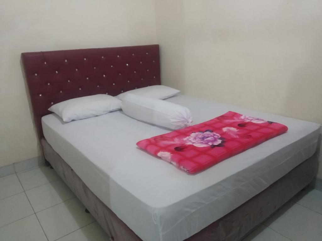 a bed with a red blanket on top of it at Modern Indekos Cilegon Syariah RedPartner in Grogol