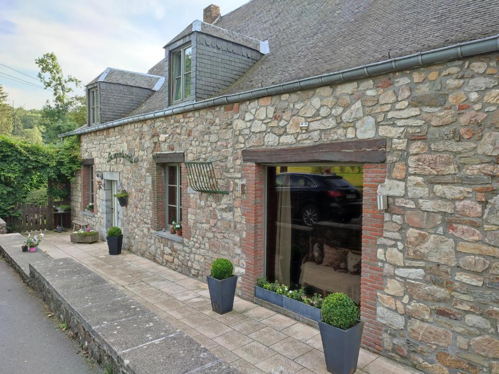 une maison en pierre avec des plantes dans une fenêtre dans l'établissement Les Arpents Verts, à Momignies