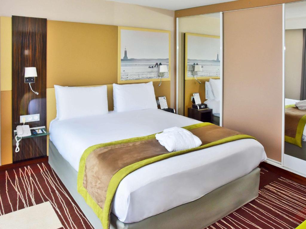 a bedroom with a large white bed in a room at Mercure Granville Le Grand Large in Granville