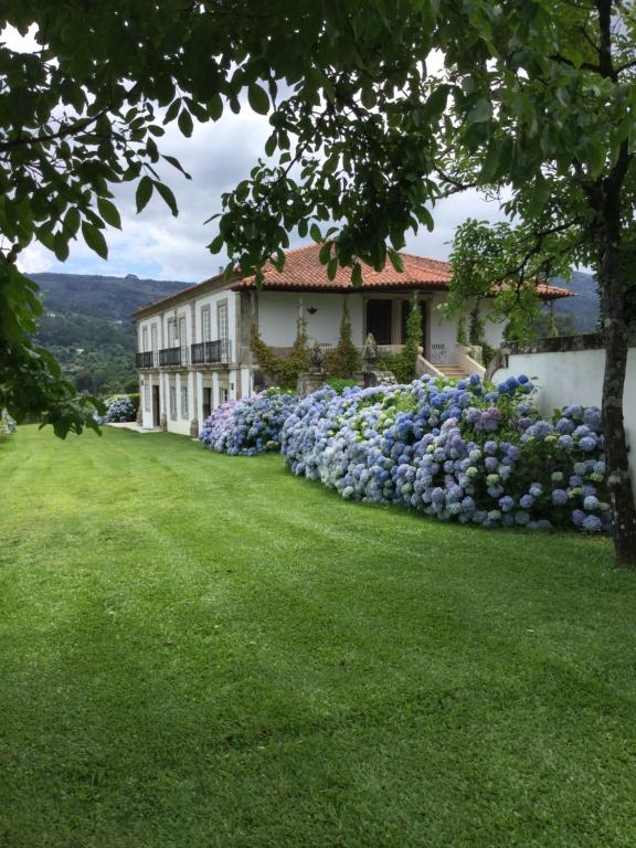 a house with blue flowers in the yard at Quinta de Luou in Santa Cruz do Lima