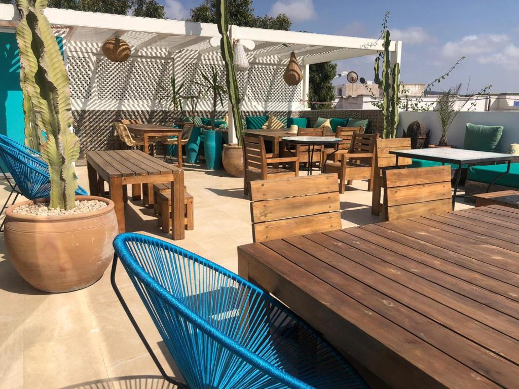a patio with wooden tables and chairs and a table and chairs at Vent Des Dunes in Essaouira