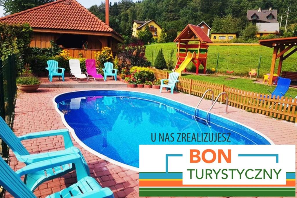 uma piscina num quintal com cadeiras e um parque infantil em Willa i domki Victoria em Wisła