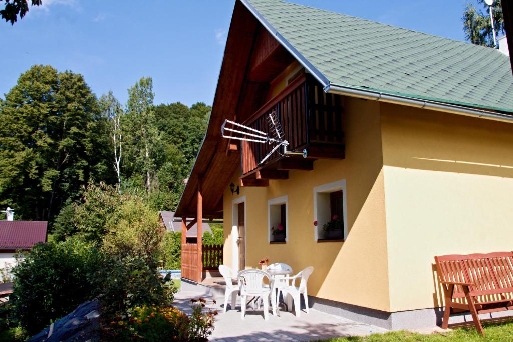 ein Haus mit einer Terrasse mit weißen Tischen und Stühlen in der Unterkunft Chata U lesa in Svoboda nad Úpou