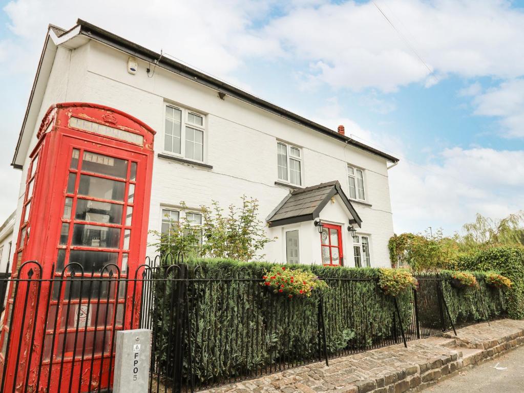 a red phone booth in front of a white house at The Old Post Office in Llandrindod Wells