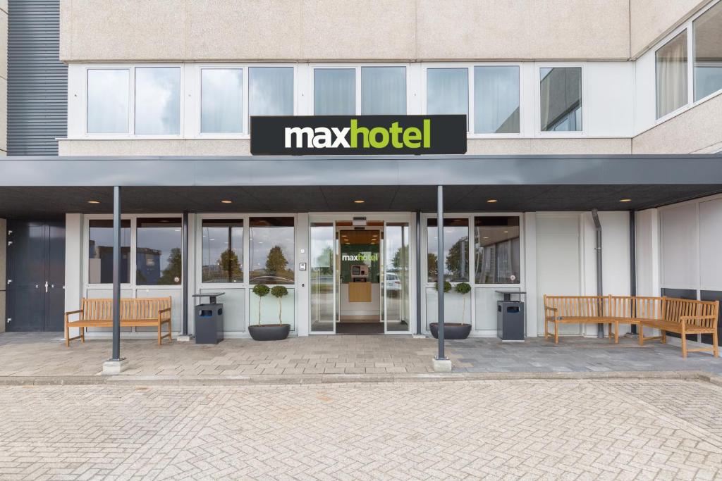 a may hotel building with two benches in front of it at Maxhotel Amsterdam Airport Schiphol in Hoofddorp
