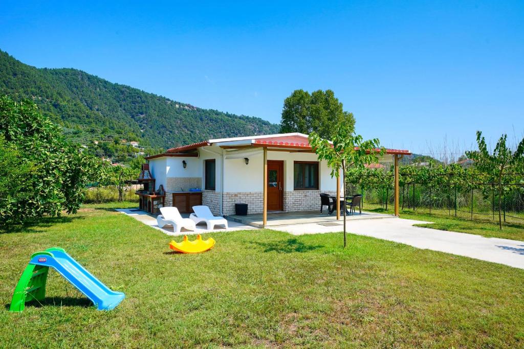 een klein huis met een glijbaan en een speeltuin bij Semiramis Cottage in Chrysi Ammoudia