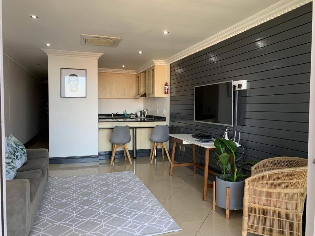 eine Küche und ein Wohnzimmer mit einem Sofa und einem TV in der Unterkunft The Sails G609 in Durban