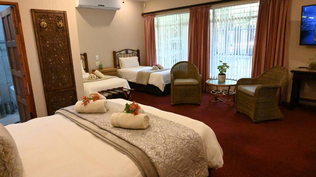 a hotel room with two beds and a television at LUXURY FAMILY EN-SUITE ROOM @ 4 STAR GUEST HOUSE in Middelburg