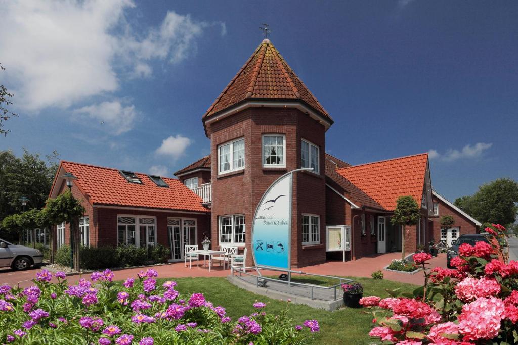 een groot bakstenen huis met een klok erop bij Landhotel Esen in Neuharlingersiel