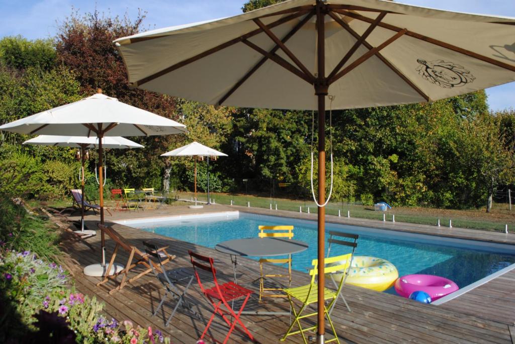 einen Pool mit Sonnenschirmen und Stühlen sowie einen Tisch mit einem Tisch in der Unterkunft Suite au château - Domaine de la Gavolerie in Bessé-sur-Braye