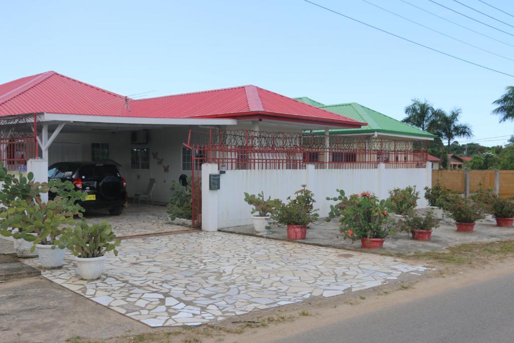 una casa con techo rojo y algunas macetas en Dubbel woonhuis Selderiestraat Paramaribo, en Paramaribo