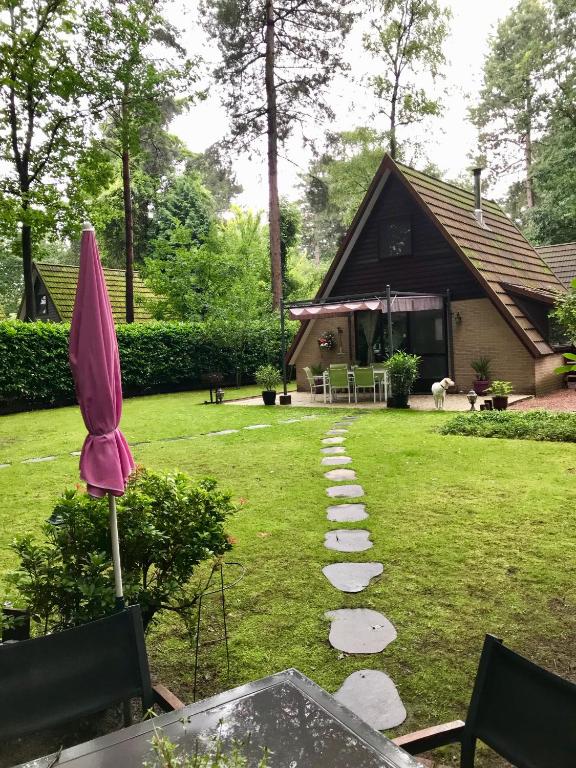 拉纳肯La Casita E41的一个带小径和粉红色遮阳伞的花园