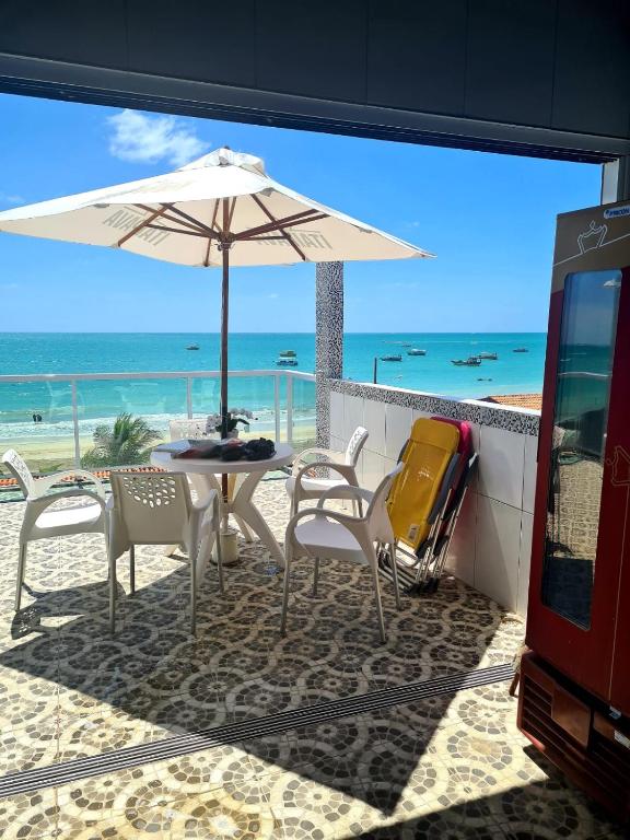 a table and chairs with an umbrella on the beach at cobertura jangadeiro RUA JANGADEIROS 215 in Maragogi