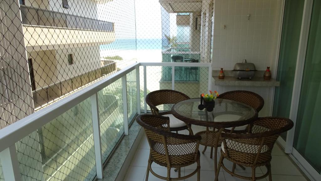 un balcón con una mesa de cristal y sillas. en Belíssimo Apto à Beira Mar, en Arraial do Cabo