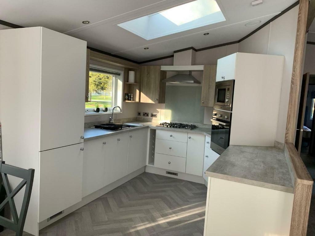 Barmby on the MoorにあるGraceland Lodge with Hot Tubの白いキャビネットと天窓付きのキッチン