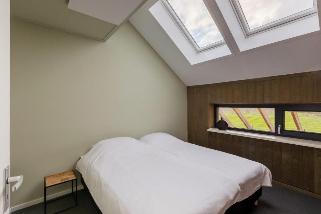 1 dormitorio con cama blanca y ventana en Holidayhome - Vroondijk 2 Vrouwenpolder 'Zeebloesem', en Vrouwenpolder