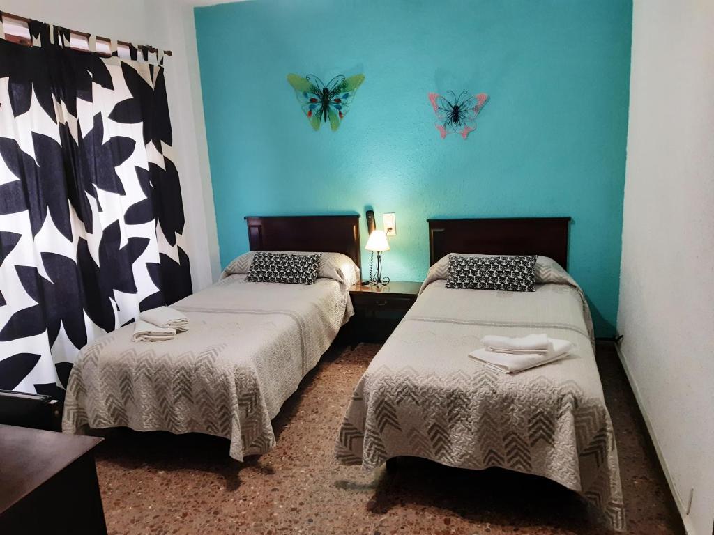 two beds in a room with butterflies on the wall at Hotel Azahar in Oliva