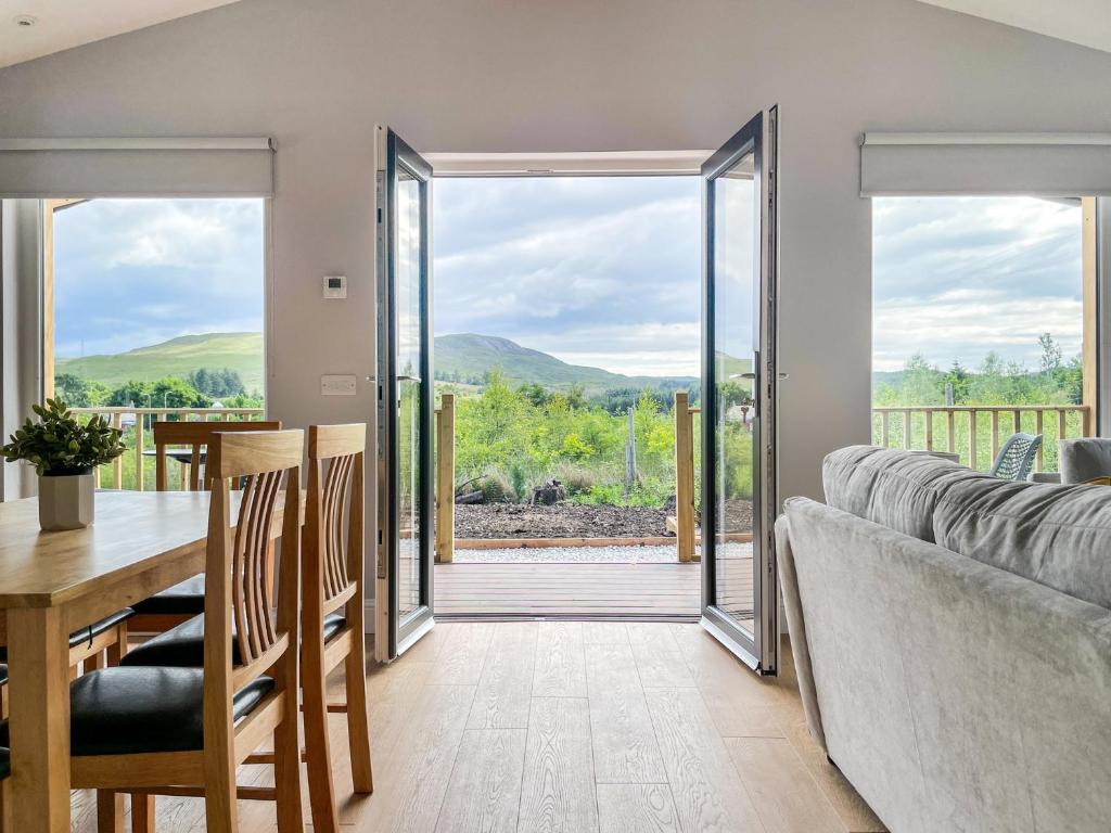 a living room with a table and a couch and glass doors at Broadford Lodges Skye in Broadford