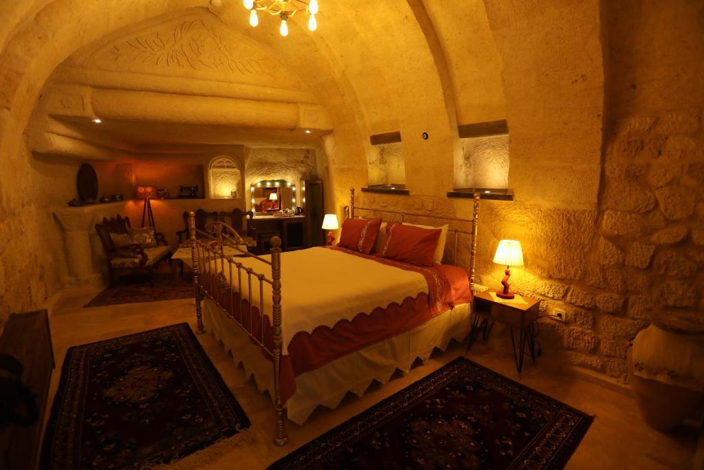 Hancı Cave Hotel في أوروغوب: غرفة نوم مع سرير في غرفة حجرية