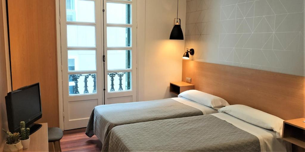 Habitación de hotel con 2 camas y TV en Roquefer Bilbao Central Rooms, en Bilbao