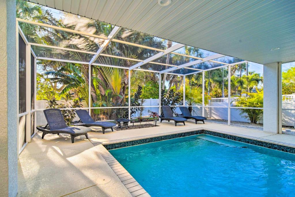 a swimming pool in a house with chairs and a house at Vibrant Island Home with Pool, 1 Block to Beach in Anna Maria