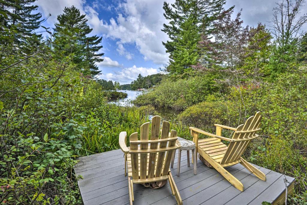 dwa krzesła i stół na drewnianym tarasie w obiekcie Warm and Cozy Adirondacks Cabin on Otter Lake! w mieście Forestport