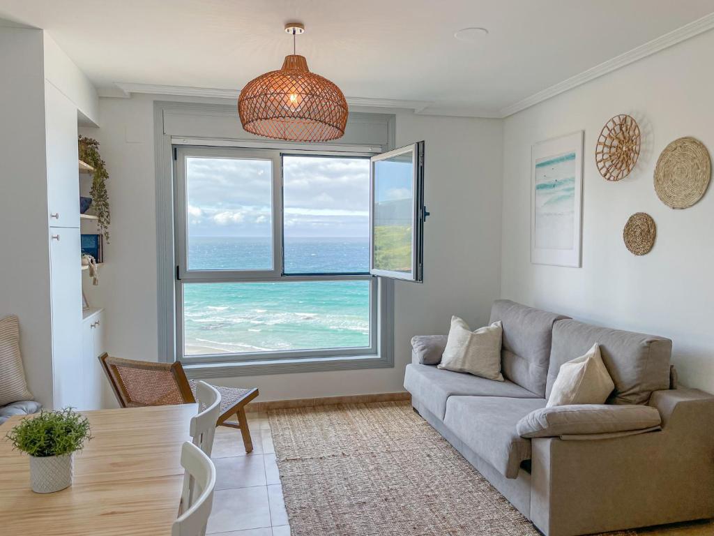 sala de estar con sofá y ventana grande en Apt ILUKA Nuevo con vistas al mar, en Malpica de Bergantiños