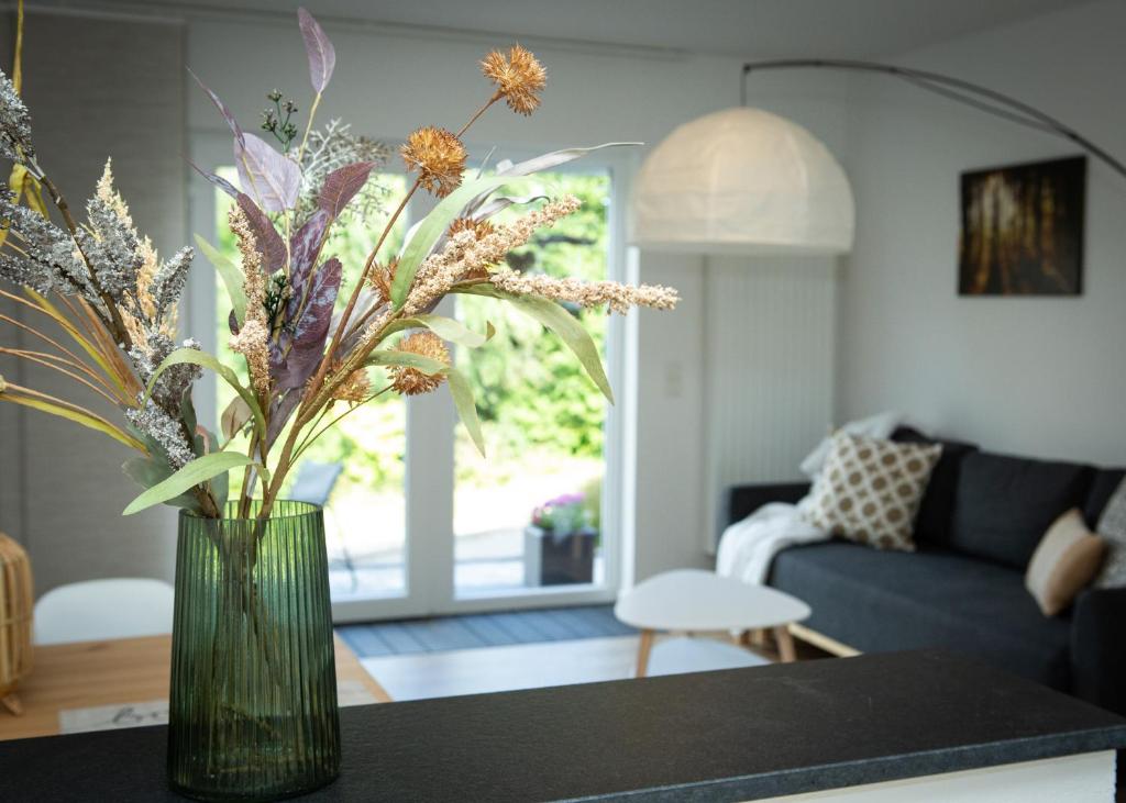 un jarrón con flores sobre una mesa en la sala de estar en The Rocks - Ferienwohnung mit Felsenpanorama en Gerolstein
