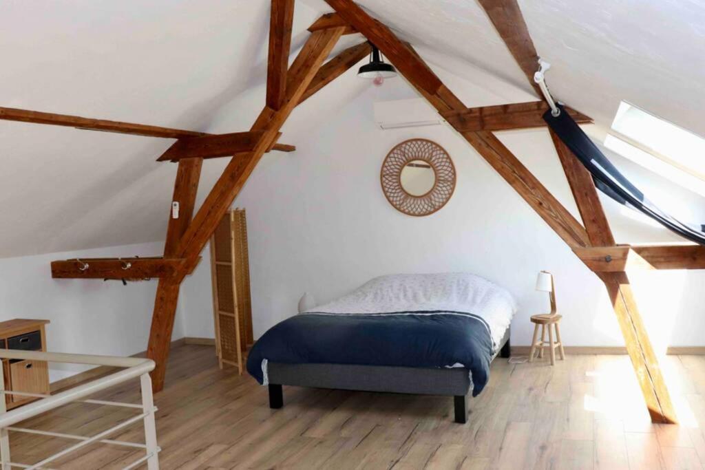 a bedroom with a bed in a attic with wooden beams at La grange de Jeanette in Burnhaupt-le-Haut