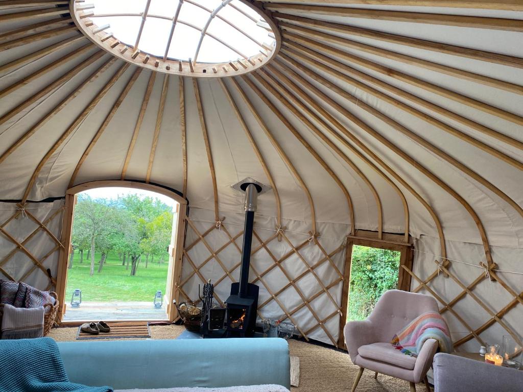 a yurt with a couch and chairs and a window at Blossom Orchard - Luxury Yurts in Langport