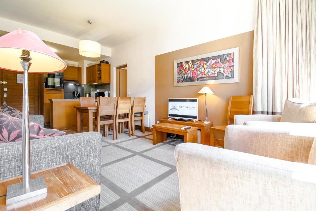 a living room with a couch and a dining room at Bright spacious two bed South facing family apartment in Flaine