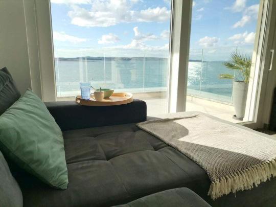 a couch in a living room with a large window at SMARAGD on the beach in Povljana