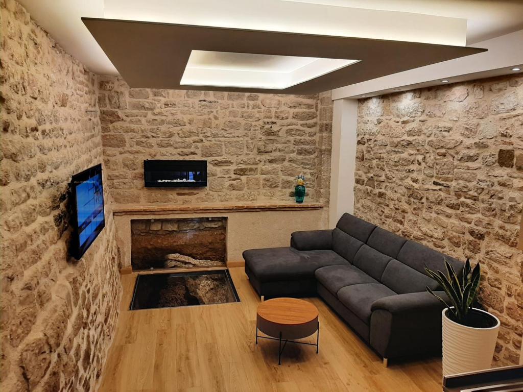 salon z kanapą i ceglaną ścianą w obiekcie Appartamento Gattapone 9 w mieście Gubbio