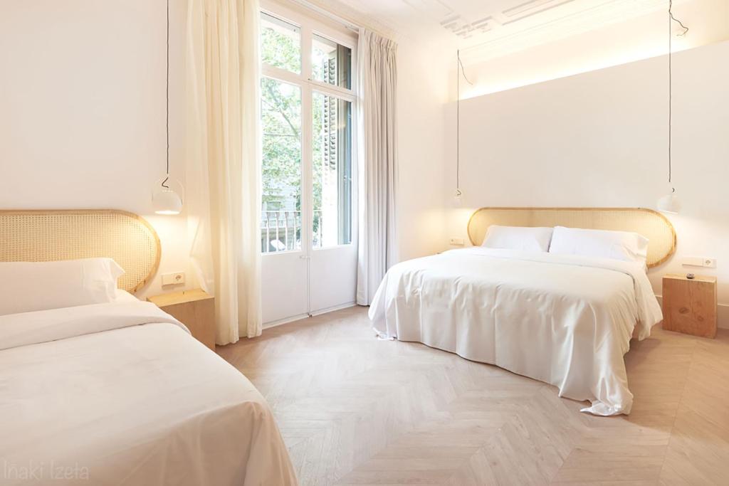 two beds in a white room with a window at The MO House in Barcelona