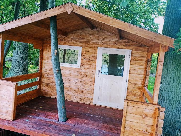 a wooden cabin with a white door on a wooden deck at Šeberák - ubytování v chatičkách a v luxusních stanech in Prague