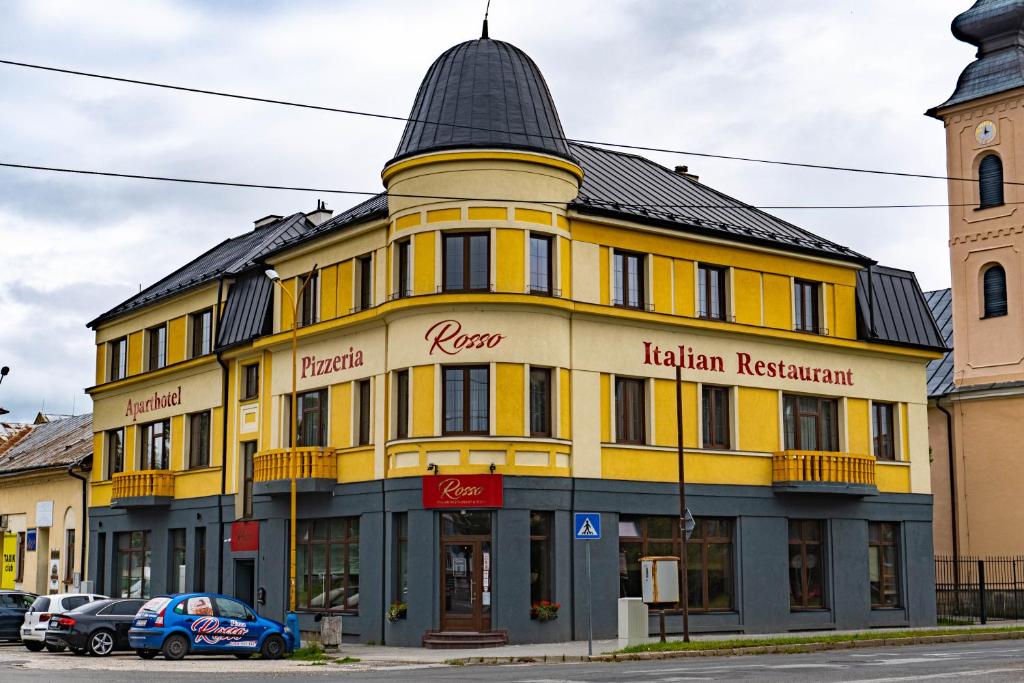 a yellow building with a black roof at Rosso Aparthotel in Michalovce