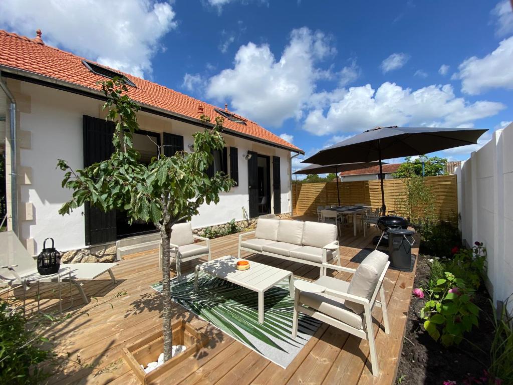 eine Holzterrasse mit einem Tisch und einem Sonnenschirm in der Unterkunft Villa du bassin -un petit coin de paradis in Andernos-les-Bains